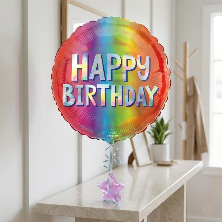 Colorful 'Happy Birthday' balloon on a table with a plant in the background