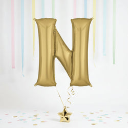 Gold letter 'N' balloon with a star-shaped confetti on a light background