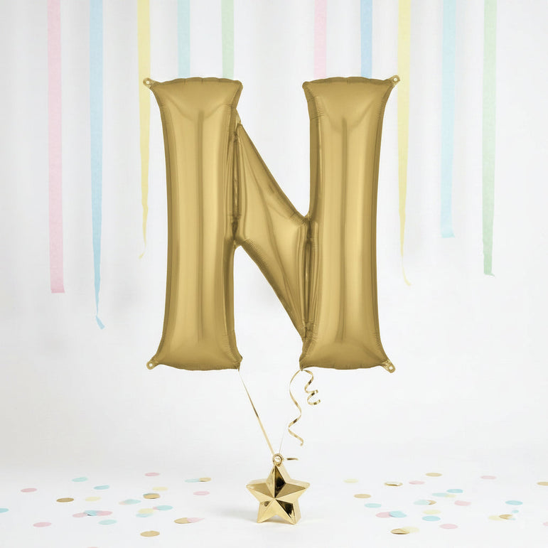 Gold letter 'N' balloon with a star-shaped confetti on a light background